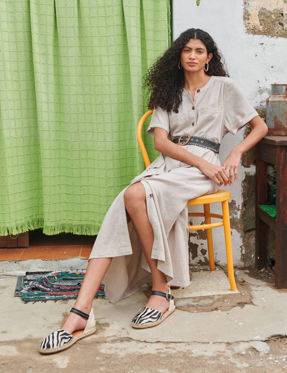 woman in pale linen dress sitting on chair